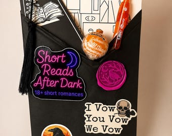 May include: A black envelope containing a TBR List card, a black bookmark with a tassel, an orange Bic pen, a caramel candy, a Short Reads After Dark sticker, a pink wax seal, an I Vow You Vow We Vow skull sticker, and a raven forest sticker.