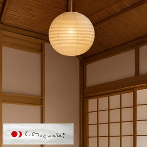 May include: A round, cream-colored paper lantern hangs from the ceiling in a room with wooden accents. The lantern is illuminated, casting a warm glow. The room features traditional Japanese-style sliding doors and wooden beams.