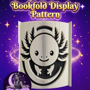 Peut inclure: Un motif de pliage de livre avec un design d'axolotl sculpté. L'axolotl a un visage souriant et des branchies plumeuses. Le texte "Bookfold Display Pattern" est en lettres dorées. Le fond est violet avec des étoiles.
