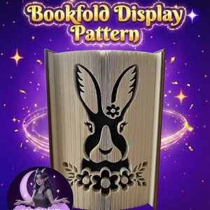 Könnte beinhalten: Ein Buchfalt-Display-Muster mit einem Kaninchen-Design, das in die Seiten geschnitten ist. Der Text "Bookfold Display Pattern" wird über dem Buch angezeigt. Der Hintergrund ist lila mit Sternen und einem Mond mit einer Frau.
