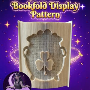 Könnte beinhalten: Ein Buchfaltmuster mit einem Topfgold- und Kleeblatt-Design. Das offene Buch zeigt die ausgeschnittene Form. Der Text "Bookfold Display Pattern" steht oben. Der Hintergrund ist lila mit Sternen und einem Mondlogo.