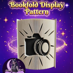 May include: A bookfold display pattern with a camera design cut out. The text "Bookfold Display Pattern" is at the top. The background is purple with stars and a crescent moon with a woman and the text "Moonlit Munchkin Creations".