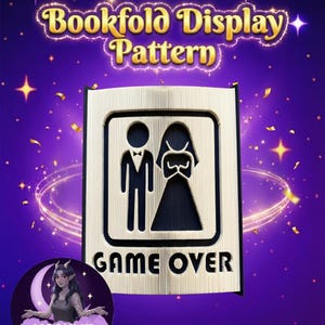 May include: A bookfold display pattern with a gold-coloured frame featuring a bride and groom silhouette and the words "GAME OVER." The text "Bookfold Display Pattern" is at the top. The background is purple with stars and confetti.