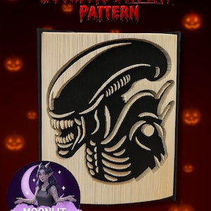 Könnte beinhalten: Ein Buchfalt-Display-Muster mit einem schwarzen Alien-Design, das in die Seiten geschnitten ist. Der Text "Bookfold DISPLAY PATTERN" steht oben in Rot. Das Logo von Moonlit Munchkin Creations befindet sich unten.