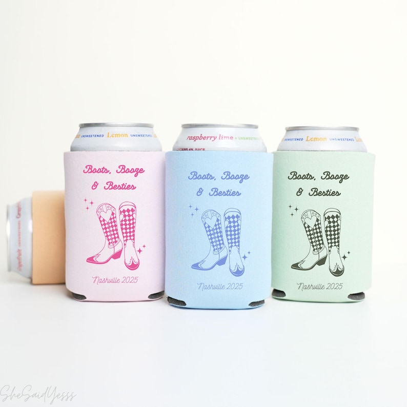 K&ouml;nnte beinhalten: Drei Getr&auml;nkedosen-K&uuml;hler in Rosa, Blau und Gr&uuml;n, jeweils mit einem Cowboy-Stiefel-Design und dem Text "Boots, Booze & Besties" und "Nashville 2025". Ein vierter beigefarbener K&uuml;hler ist teilweise sichtbar.