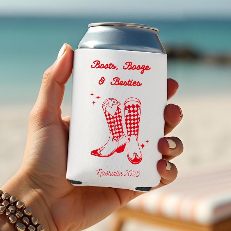 K&ouml;nnte beinhalten: Ein wei&szlig;er Getr&auml;nkedosenk&uuml;hler mit rotem Text und Grafiken. Der Text lautet "Boots, Booze & Besties" und "Nashville 2025". Die Grafik zeigt zwei rote Cowboy-Stiefel mit Herz- und Karomustern.