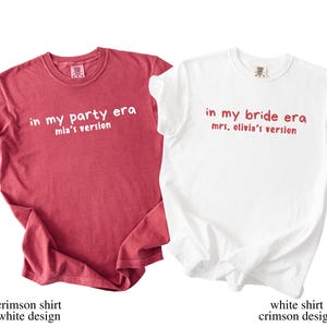 May include: Two t-shirts, one crimson and one white, with text. The crimson shirt reads "in my party era, mia's version" in white. The white shirt says "in my bride era, mrs. olivia's version" in crimson. Both are short-sleeved.