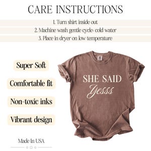 May include: A brown t-shirt with the text "SHE SAID Yesss" in a cursive font. The shirt has rolled-up sleeves and is displayed on a white background. Additional text includes "Super Soft", "Comfortable fit", "Non-toxic inks", and "Vibrant design".