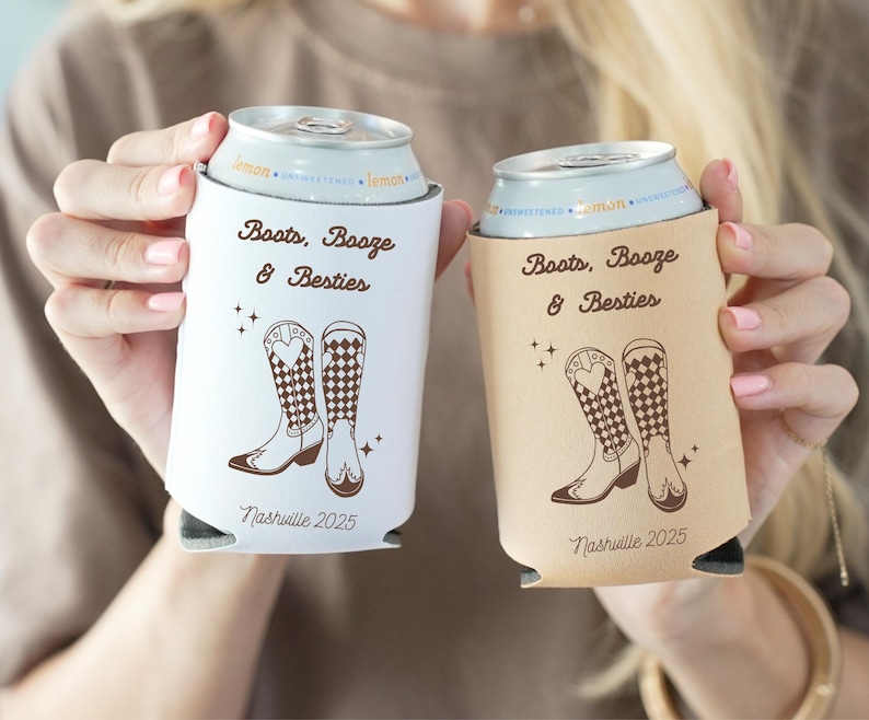 K&ouml;nnte beinhalten: Zwei Getr&auml;nke-K&uuml;hlmanschetten, eine wei&szlig;e und eine beige, mit dem Text "Boots, Booze & Besties" und "Nashville 2025". Jede hat eine braune Illustration von Cowboy-Stiefeln. Zum K&uuml;hlen von Getr&auml;nken.