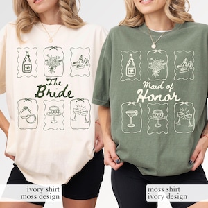 May include: Ivory and moss green t-shirts with matching graphic designs. The ivory shirt says "The Bride" and the moss green shirt says "Maid of Honour". Each shirt features illustrations of wedding-related items.