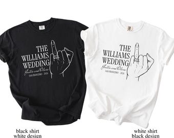 May include: Two t-shirts, one black and one white, each featuring a graphic of a hand with a ring on the middle finger. The text reads "THE WILLIAMS WEDDING Justin and Olivia SAN FRANCISCO - 2026".
