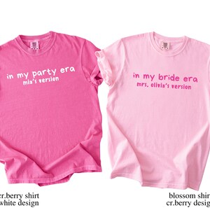 May include: Two pink t-shirts with text. One is a bright pink shirt with the text "in my party era mia's version" in white. The other is a light pink shirt with the text "in my bride era mrs. olivia's version" in pink.