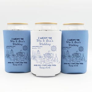 May include: Three can coolers, two in light blue and one in white, each with the text "I WENT TO Wes & Ana's Wedding" and event details. The design includes a line drawing of a wedding reception scene. The phrase "AND ALL I GOT WAS THIS lousy shirt" is also printed.