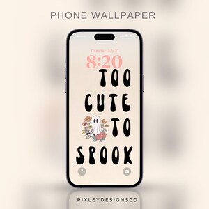 Op de afbeelding: Een smartphone toont een telefoonachtergrond met de tekst "TOO CUTE TO SPOOK" in zwart, met een spookillustratie en bloemaccenten. Het scherm van de telefoon toont de datum en tijd. De woorden "PHONE WALLPAPER" staan bovenaan.
