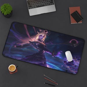 May include: A large rectangular mousepad featuring a fantasy character with long blonde hair, wearing a dark outfit, and surrounded by a cosmic background with purple and blue hues. A white mouse is on the right side.