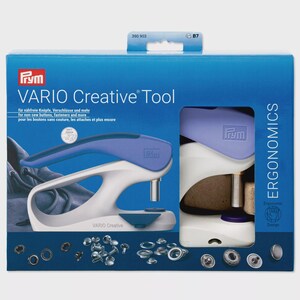 May include: A blue and white VARIO Creative Tool kit by Prym. The kit includes a tool for non-sew buttons, fasteners, and more. The box also shows various metal fasteners and the word "ERGONOMICS".