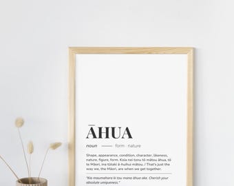 May include: A framed print with the word "AHUA" in bold, black letters. The print includes a definition and a quote in a foreign language. The frame is light-colored wood. A small vase with dried flowers sits to the left of the frame.