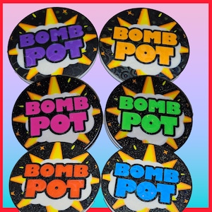 May include: Six round coasters with the text "BOMB POT" in various colors: purple, orange, pink, green, blue, and yellow. Each coaster has a black background with a yellow explosion design.
