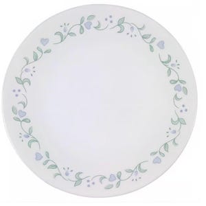 May include: White round plate with a floral design. The plate features a border of green vines, small purple dots, and light blue heart-shaped flowers. A simple and elegant design for everyday use.
