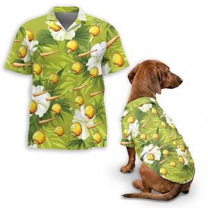 Könnte beinhalten: Ein grünes Hawaiihemd mit einem Muster aus gelben Softbällen, weißen Blumen und braunen Schlägern. Ein Dackel trägt ein passendes Hemd. Das Hemd hat kurze Ärmel und eine Knopfleiste.