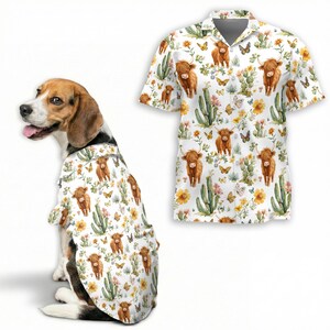 May include: A white button-up shirt with a Highland cow, cactus, and butterfly pattern. A dog is wearing a matching shirt. The shirt has short sleeves and a collar. The pattern includes yellow flowers and green cacti.