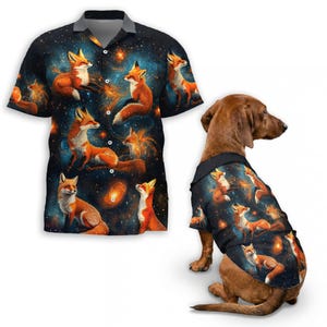 May include: A short-sleeved button-down shirt and a dog shirt, both featuring a repeating pattern of orange foxes against a dark blue and purple galaxy background. The dog shirt is worn by a brown dachshund.