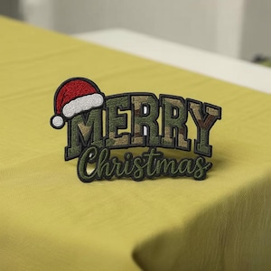 May include: Embroidered patch with the words "MERRY Christmas" in a camouflage pattern, topped with a red and white Santa hat. The patch has a dark green border and is set against a yellow background.