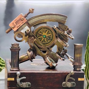 Peut inclure: Un sextant en laiton doté d'une boussole centrale avec un motif de fleur de lys, monté sur une boîte en bois sombre avec des loquets métalliques. L'instrument comprend une plaque en cuivre gravée J. SCOTT London 1753 et divers objectifs.