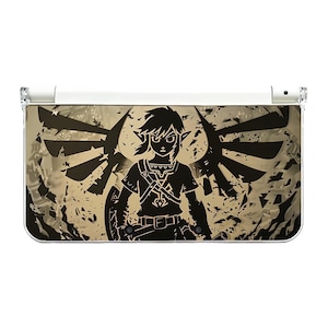 May include: A white and clear Nintendo 3DS case featuring a black silhouette of Link from The Legend of Zelda. The background has a distressed gold texture with black wing designs. The case is designed to protect the handheld gaming device.