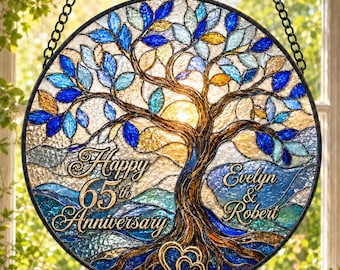 May include: A circular stained glass suncatcher featuring a tree with blue, gold, and clear textured glass leaves. The text reads Happy 65th Anniversary and Evelyn & Robert. A gold heart is at the base of the tree trunk, suspended by a black chain.