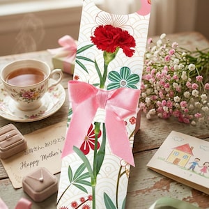 Könnte beinhalten: Eine Geschenkbox mit einer roten Nelke und einer rosa Schleife. Die Box hat ein Blumendesign mit grünen und roten Akzenten. Eine Tasse und Untertasse, eine Karte mit "Happy Mother's" und eine kleine Geschenkbox sind ebenfalls im Bild.