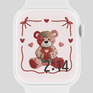 以下が含まれることがあります： 白いスマートウォッチ。パッチワークのテディベアがハートを持っているカスタムフェイス。クマは赤いハートとリボンに囲まれ、時刻2:14がデジタル表示されています。
