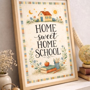May include: A framed print with the words "HOME sweet HOME SCHOOL" in a decorative font. The artwork features a watercolor illustration of a house, sun, moon, flowers, books, pencils, and an apple. The frame is light brown.