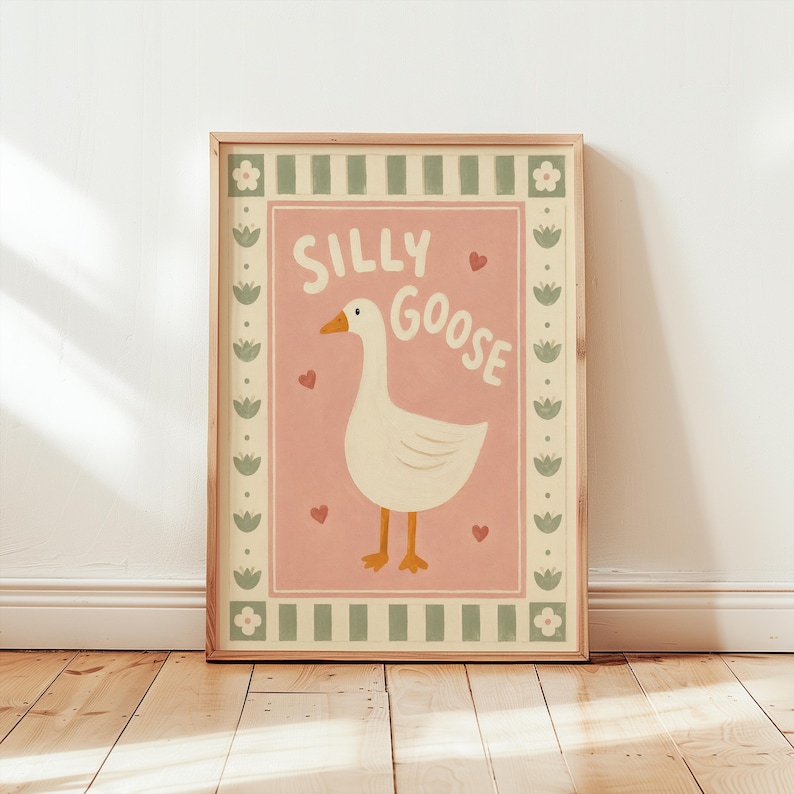 May include: A framed wall art print featuring a white goose on a pink background with the text SILLY GOOSE in white letters. The design includes small red hearts and a border with alternating green stripes, white flowers, and green tulip icons.