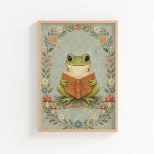 May include: A framed art print featuring a green frog reading a book. The frog is centered, holding an open book with a brown cover. The background is a light blue with a floral border and mushrooms.