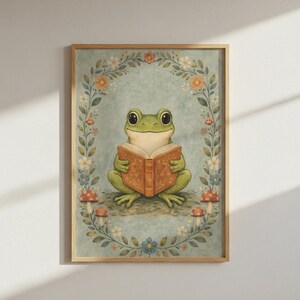 May include: A framed art print featuring a whimsical illustration of a green frog reading a book. The frog is surrounded by a floral wreath with mushrooms at the bottom. The artwork has a vintage, storybook aesthetic.