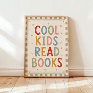 May include: A framed poster with the text "COOL KIDS READ BOOKS" in colorful letters. The poster has a cream-colored background with a green and white striped border and star accents. The frame is made of light-colored wood.