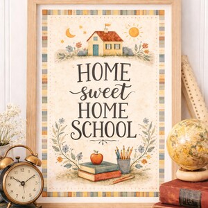 May include: A framed print with the words "Home Sweet Home School" in a decorative font. The artwork features a watercolor illustration of a house, sun, moon, and books. A vintage alarm clock and globe are in the foreground.