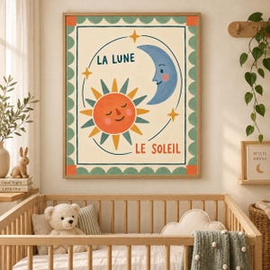 May include: A rectangular wall art print featuring a stylized orange sun and a blue crescent moon with faces. The text LA LUNE and LE SOLEIL are printed in blue and orange. The border has a green scalloped pattern with orange corners.