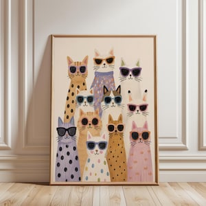 May include: A framed wall art print featuring a group of ten stylised cats wearing colourful sunglasses. The cats have various coat patterns including spots, stripes, and solid colours, and are arranged in a vertical cluster against a cream background.