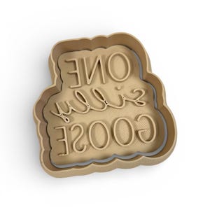 May include: A tan-colored cookie cutter in the shape of a cloud. The words "ONE" and "GOOSE" are written in a cursive font, and the numbers "2003" are written in a block font.