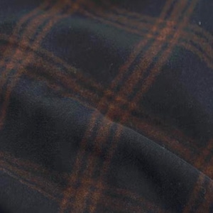 Könnte beinhalten: Nahaufnahme eines dunklen Stoffes mit Karomuster. Der Stoff ist ein tiefes Marineblau mit einem kontrastierenden braunen Gitterdesign. Die Textur wirkt weich und leicht strukturiert.