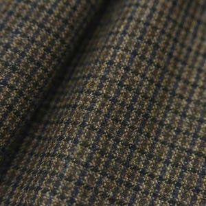 Puede incluir: Primer plano de una tela con estampado de pata de gallo. La tela presenta una mezcla de hilos marrones, beige y azul marino, creando un patrón clásico. El tejido es visible, agregando profundidad y detalle al material.