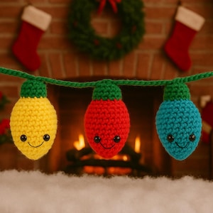 May include: A string of three crocheted Christmas light ornaments in yellow, red, and blue, each with a green cap and smiling face. The lights are strung on a green yarn, with a fireplace and Christmas decorations in the background.
