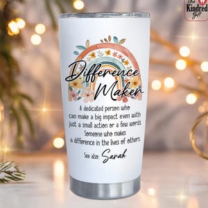 May include: White 20 oz tumbler with a rainbow and floral design, and the words "Difference Maker." The tumbler includes the text: "A dedicated person who can make a big impact..." and "See also: Sarah."