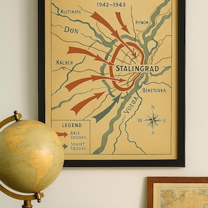 May include: Framed vintage map print titled "Battle of Stalingrad" depicting the turning point of WWII, 1942-1943. The map shows troop movements with arrows, geographical features, and place names. A globe and books are in the foreground.