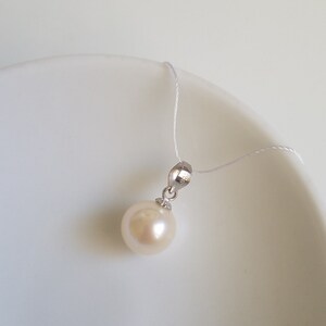 May include: A white pearl pendant on a silver chain. The pearl is round and smooth, and the chain is delicate.