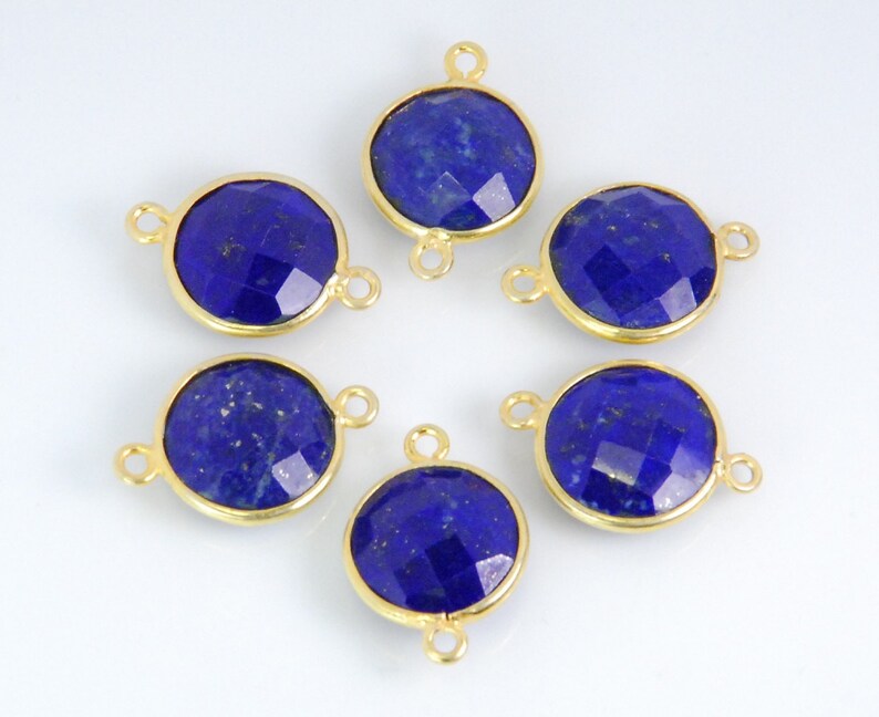 Pode incluir: Seis pingentes redondos de conex&atilde;o de pedra preciosa em tom dourado com uma pedra de l&aacute;pis-laz&uacute;li em cada um. As pedras s&atilde;o facetadas e t&ecirc;m uma cor azul profunda.