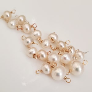 May include: A collection of luminous, off-white pearls with gold-colored wire loops. The pearls vary in size and shape, creating a natural, organic aesthetic. The gold wire adds a touch of elegance to these jewelry components.