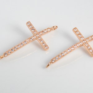 May include: Two gold-tone cross charms with clear crystal embellishments. Each charm has a loop at the top for attaching to a necklace or bracelet.